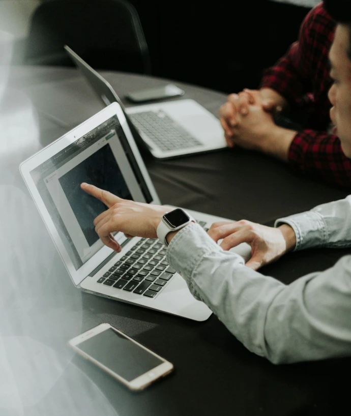 two people sitting at a table with laptops